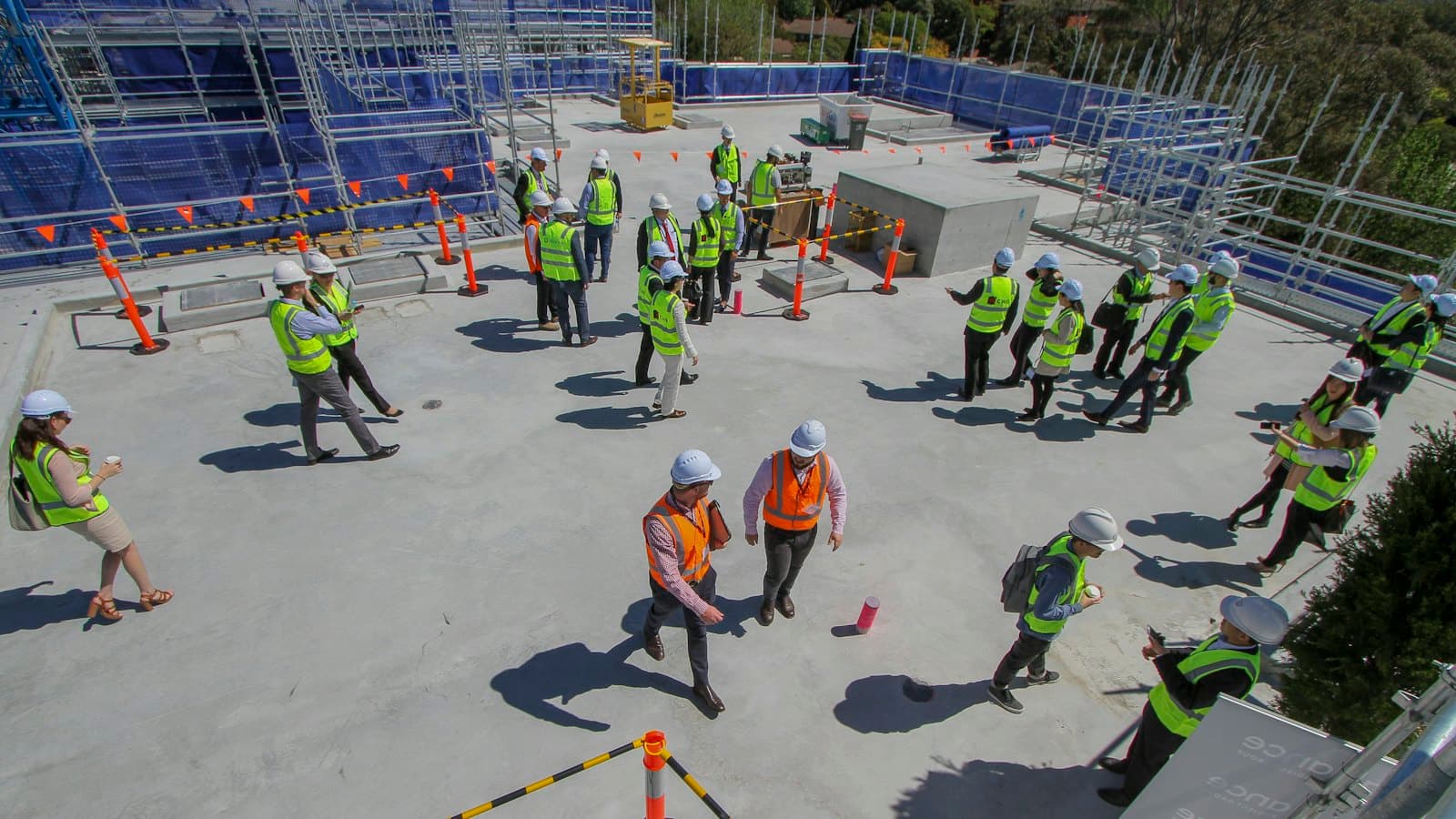 A project team in hard hats and high-visibility vests walking a building site