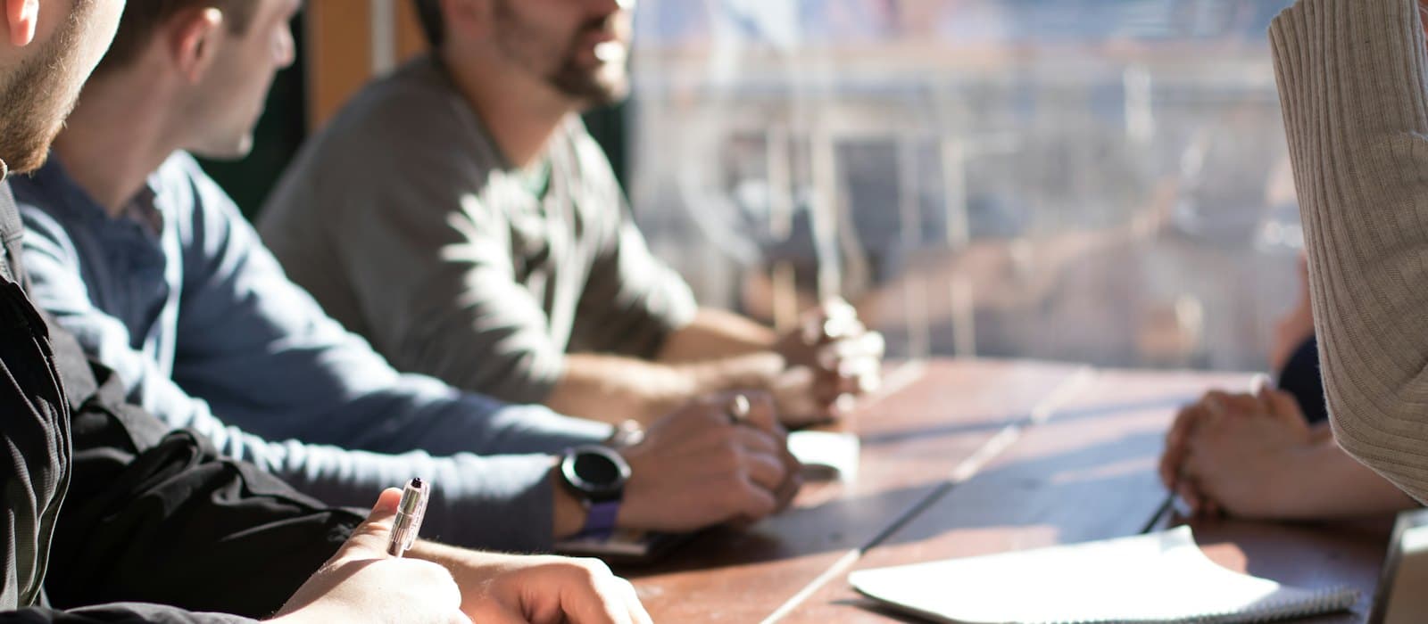 People around a table in conversation, taking notes